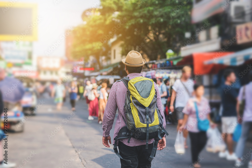 Young asian traveller man walking in Khaosan Road walking street in bangkok thailand on vacation time.