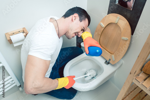 Man is a bit disgusted cleaning the toilet photo