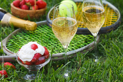 Enjoing in Wimbledon tennis championship with champagne and strawberries with cream. Wimbledon symbols on green grass. photo