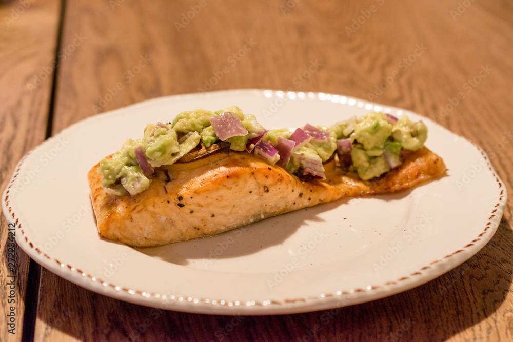 Salmon Fillet with Avocado in Plate at Dinner Table.