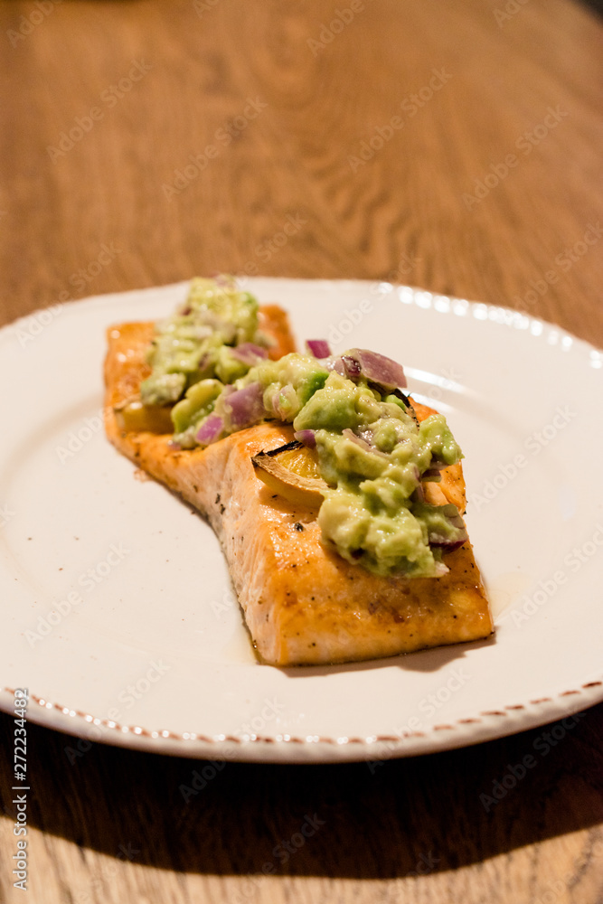 Salmon Fillet with Avocado in Plate at Dinner Table. Salmon Fillet with Avocado in Plate at Dinner Table.