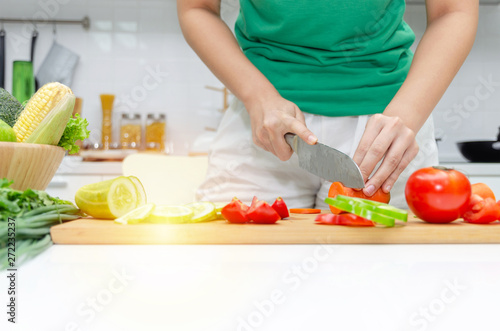 Diet. young pretty woman in green shirt cutting cooking and knife preparing fresh vegetables salad for good healthy in kitchen at home  healthy lifestyle  cooking  healthy food and dieting concept