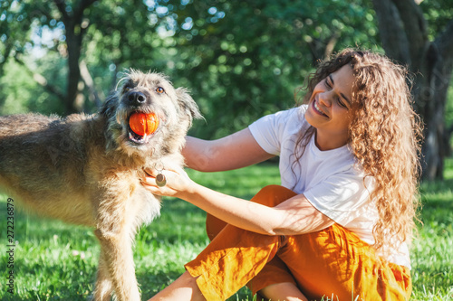 Obraz na płótnie Young happy charming girl playing with her dog with a ball in the park w salonie
