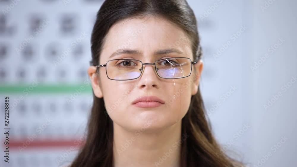 Sad lady in broken glasses looking to camera and crying suffering poor vision Sad lady in broken glasses looking to camera and crying suffering poor vision