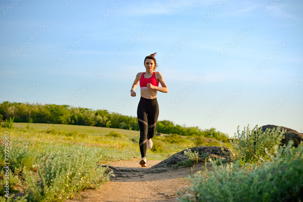 Young Beautiful Woman Running on the Mountain Trail in the Hot Summer Evening. Sport and Active Lifestyle. Young Beautiful Woman Running on the Mountain Trail in the Hot Summer Evening. Sport and Active Lifestyle.