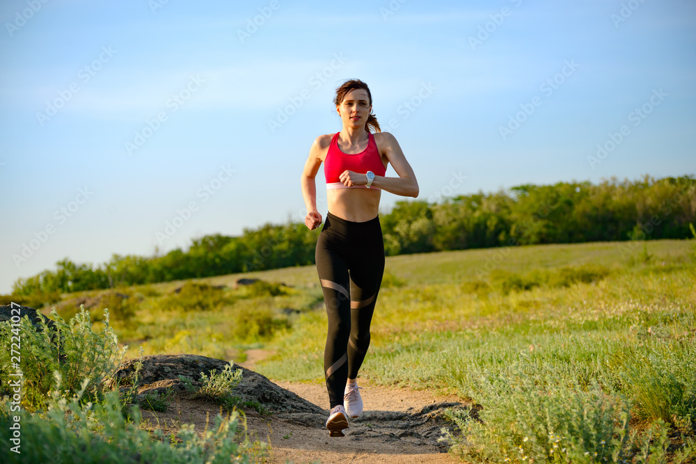 Young Beautiful Woman Running on the Mountain Trail in the Hot Summer Evening. Sport and Active Lifestyle. Young Beautiful Woman Running on the Mountain Trail in the Hot Summer Evening. Sport and Active Lifestyle.
