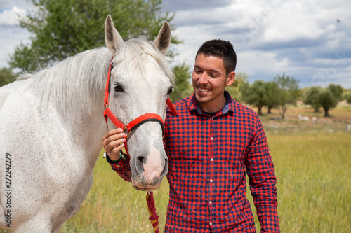 Young man touching white horse affectionately