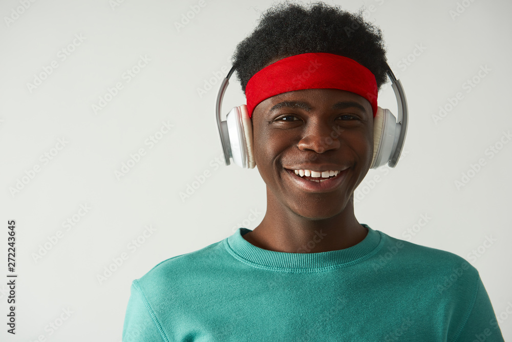 Smiling Afro American guy is using headphones Smiling Afro American guy is using headphones