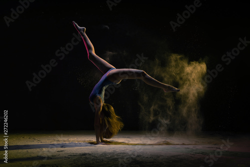 Female dancer doing handstand under colorful light