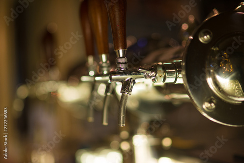 Three vintage golden beer taps in the bar, blurry background. Detail on beer faucet.