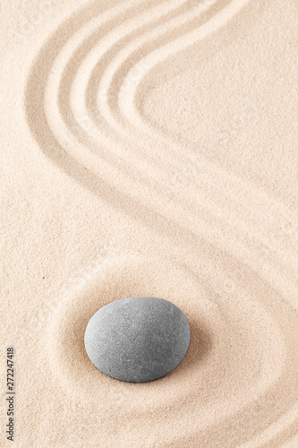 Zen garden meditation stone. Round rock on sandy texture background. Yoga or mindfulness concept.