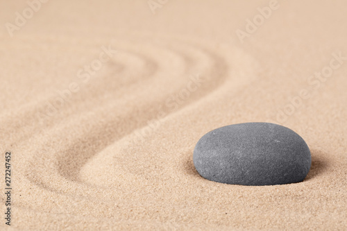 Japanese zen meditation garden with a round stone on sandy background with copy space. Concept for concentration focus and balance in life.