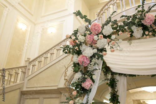Beautiful wedding huppah decorated with fresh fresh flowers from hydrangea and eucalyptus sheets in a large beautiful wedding hall with a balcony. Wedding floristry © Kate