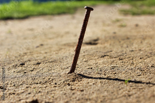Old rusty nail sticking out of the ground.