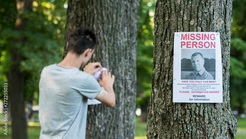 A young man puts up ads for a missing person in the park