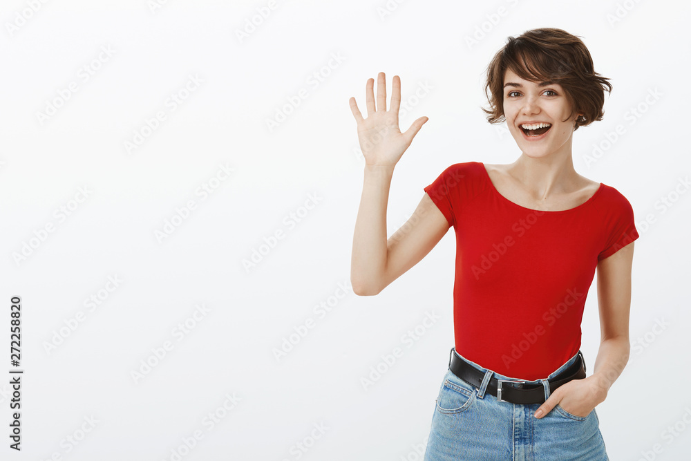 Hey whats up. Attractive sociable cheerful friendly european girl short haircut waving raised palm say hi hello greeting you welcoming guests stand white background meet new people Hey whats up. Attractive sociable cheerful friendly european girl short haircut waving raised palm say hi hello greeting you welcoming guests stand white background meet new people