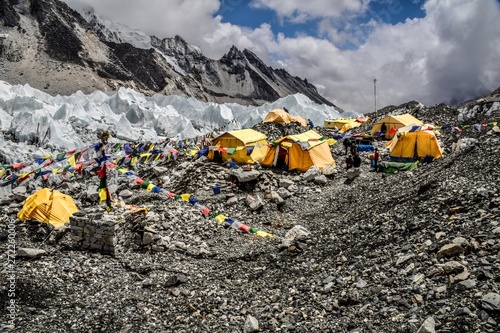 Everest base camp yellow tents and Tibetan flags with mountains and ice on background