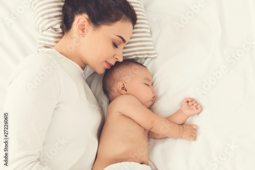 Young mom and her cute baby sleeping in bed