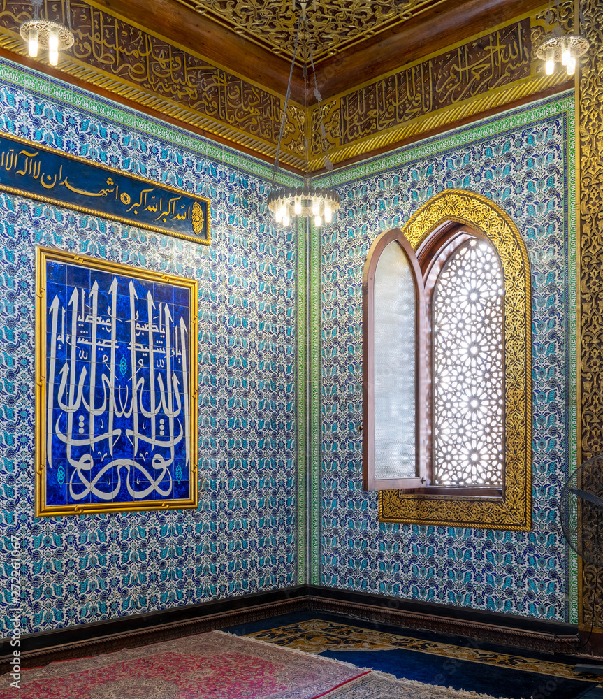 Turkish blue floral pattern ceramic tiles wall with wooden arched decorated window and moral with Arabic calligraphy at the public mosque of Manial Palace of Prince Mohammed Ali, Cairo, Egypt