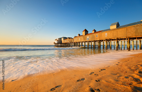 Beautiful sunrise over Old Orchard Beach Pier, Saco Maine USA. The wooden pier on the beach contains many other tourist businesses, including a variety of souvenir shops. photo