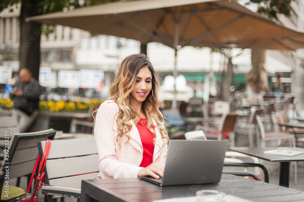 Young woman blogger freelancer in outdoor cafe with computer laptop