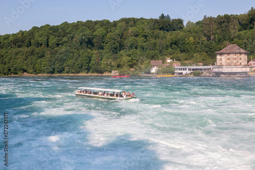 Boat with people floating to the waterfall the Rhine Falls © TravelFlow