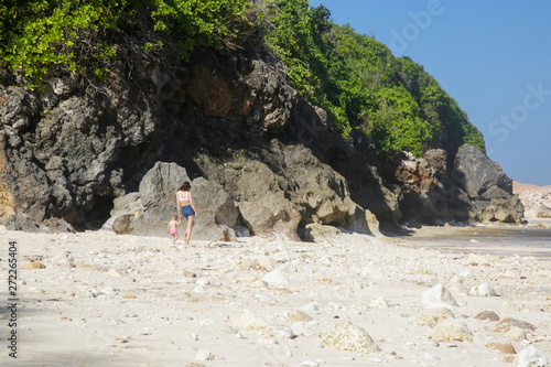 Happy playful toddler girl enjoying the beach day with her mother, family summer vacation concept