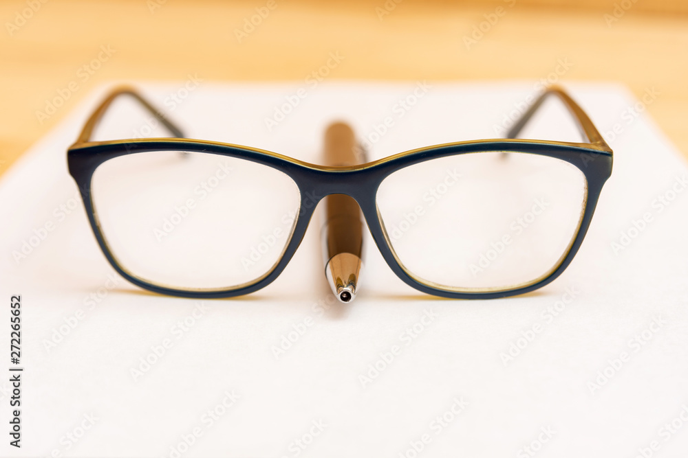 Eyeglasses lie on the handle in the shape of a nose, on a clean and white sheet of paper. Eyeglasses lie on the handle in the shape of a nose, on a clean and white sheet of paper.