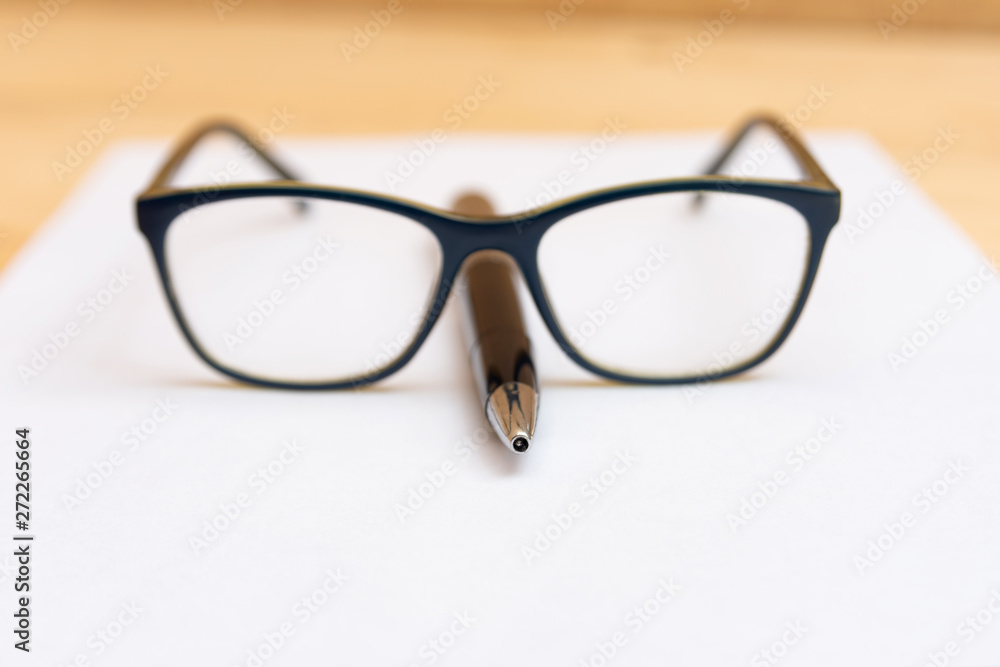 Eyeglasses lie on the handle in the shape of a nose, on a clean and white sheet of paper. Eyeglasses lie on the handle in the shape of a nose, on a clean and white sheet of paper.