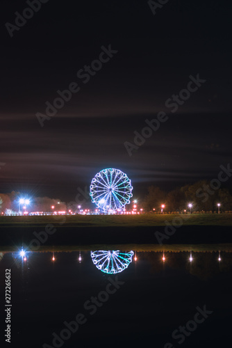 Reflection of the Ferris wheel in the water on a spring night in the Oka pearl near Ryazan