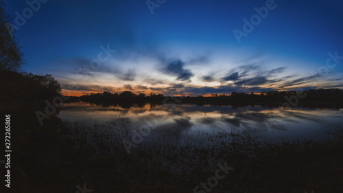 Large panorama of the most beautiful, scarlet sunset over the river in the spring