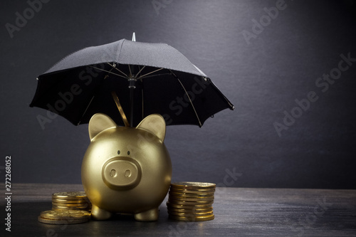 Gold Piggy bank with umbrella concept for finance insurance, protection, safe investment or banking photo