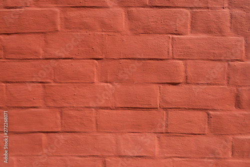 Red brick wall with smooth seams, covered with lime or plaster
