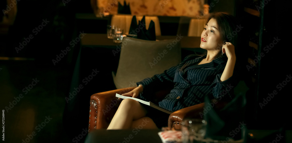 Asian mature sexy female sitting in cafe reading a book