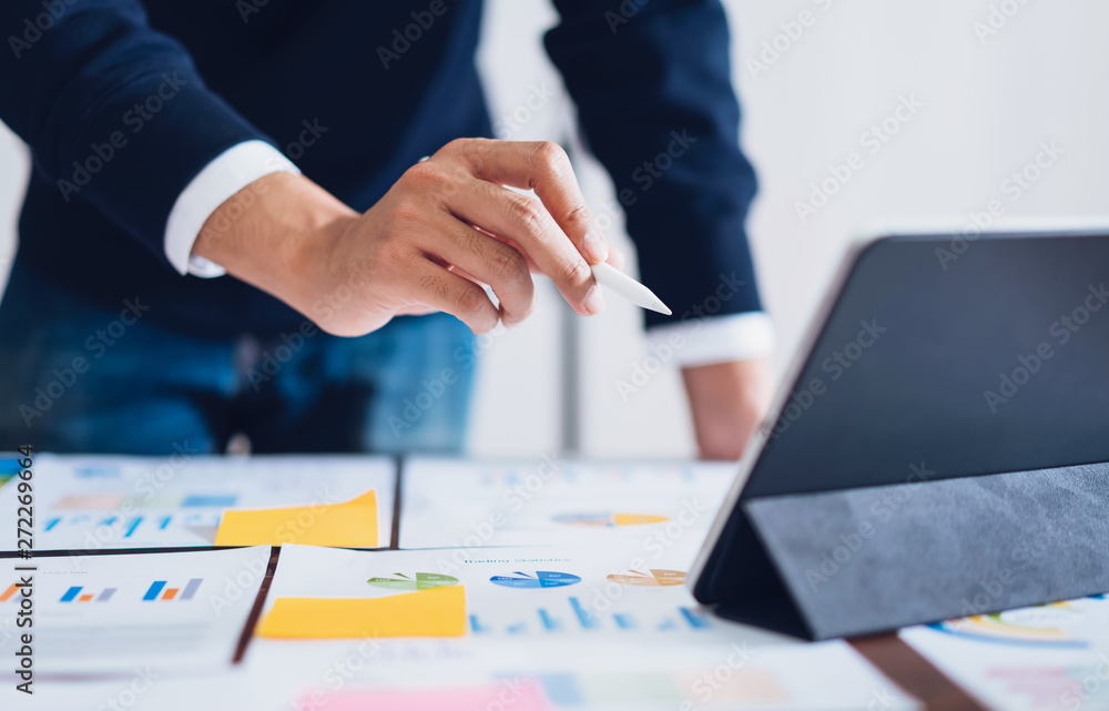 Businessman pointing digital pens to tablet and working on the table and financial documents in office. successful workplace strategy. Businessman pointing digital pens to tablet and working on the table and financial documents in office. successful workplace strategy.