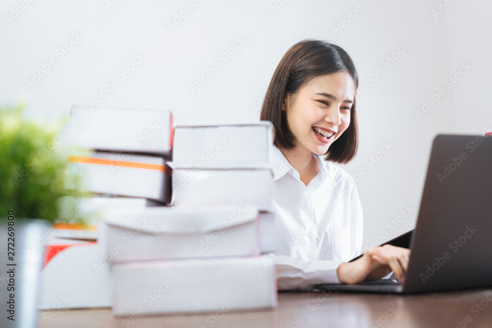 Happy smiling Asian woman using laptop computer checking order for customer and online delivery for ready packaging. Happy smiling Asian woman using laptop computer checking order for customer and online delivery for ready packaging.