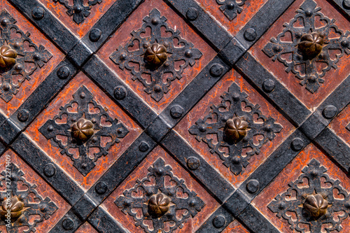 Ancient gate with metal mounting and ironworks. Beautiful decorative metal elements forged wrought iron gates.