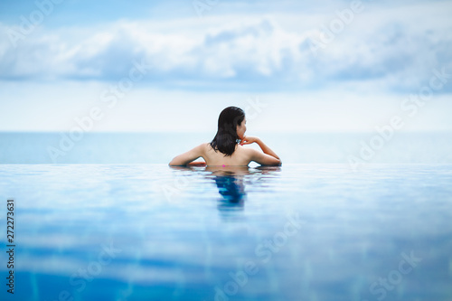 Asian woman relax in pool on beach