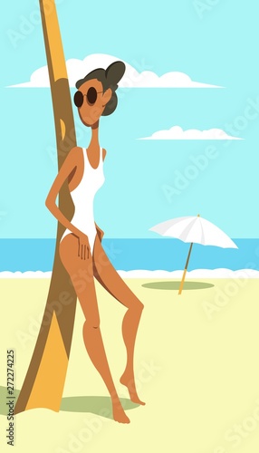 tanned girl in a white bathing suit stands leaning against a palm tree