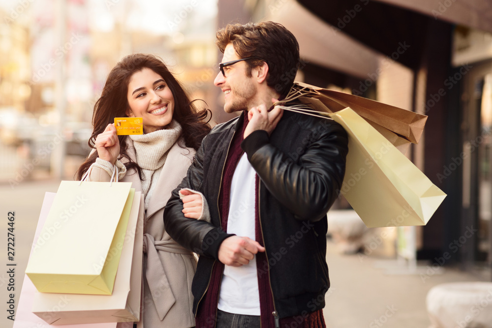Shopping together. Woman showing credit card to husband Shopping together. Woman showing credit card to husband