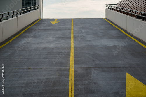 Wallpaper Mural Asphalt road, driveway to multi-storey parking lot, garage with grunge surface texture and contrasting yellow color of traffic markings, arrows. View from bottom. Torontodigital.ca