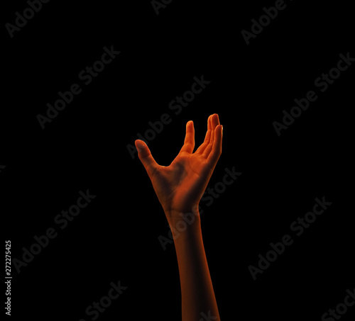 Isolated hand reaching to grab some source of light in the black background.