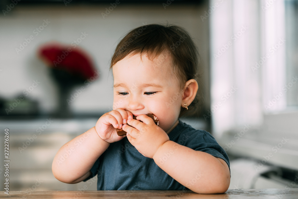 little girl in the afternoon in the kitchen eating a delicious chocolate bar little girl in the afternoon in the kitchen eating a delicious chocolate bar