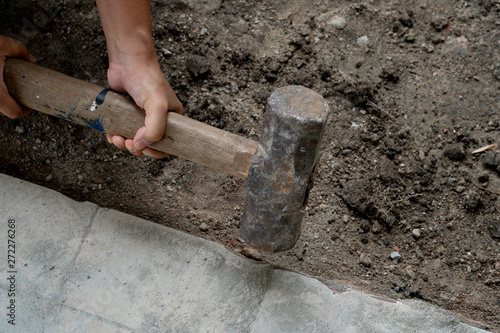 Construction worker : The second hand holds the hammer to knock the tiles out on the ground. © thongchainak