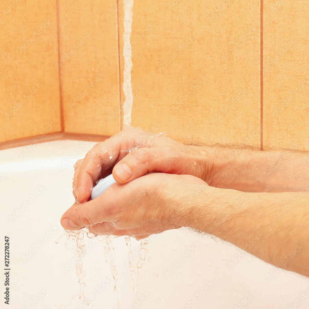 Hands of man with soap under running water in the bathroom Hands of man with soap under running water in the bathroom