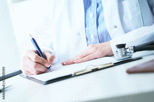 Female medicine doctor hand holding silver pen writing something on clipboard close-up. Ward round  patient visit check  medical calculation and statistics concept.