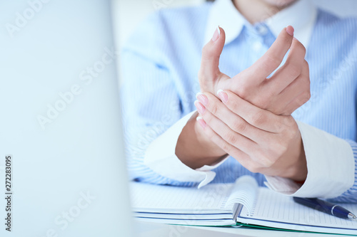 Young woman holding her wrist close-up . Pain from using computer. Office syndrome hand pain by occupational disease.