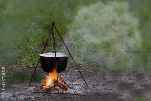 Outdoor country side cuisine with cauldron metal pot kettle for cooking outdoor in the middle of the nature near the camp with the campfire, cooking at the camp fire traditional dish. Space for text