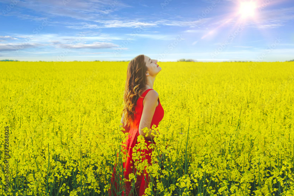 Young beautiful girl in a red dress close up in the middle of yellow field with radish flowers and sunlight.. Young beautiful girl in a red dress close up in the middle of yellow field with radish flowers and sunlight..