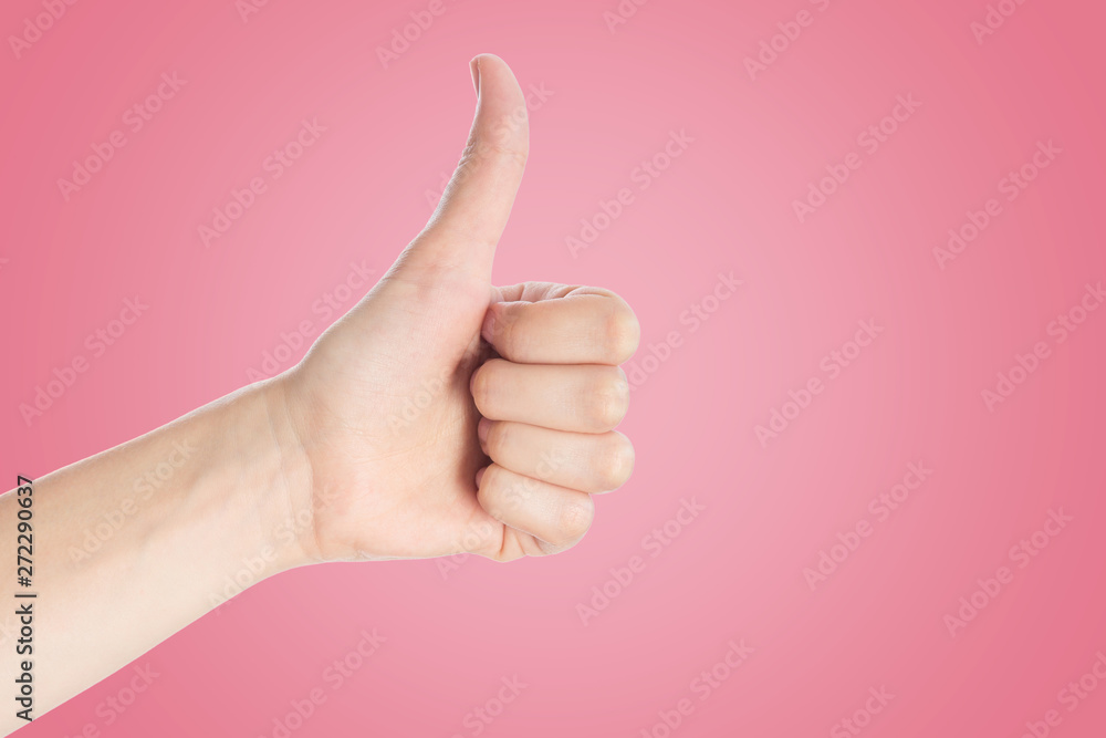 Positive gesture on a pink background. Hand show thumbs up sign, close up